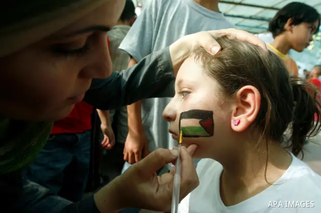 A Palestinian child paints a national flag on his face during a rally on 13 July, 2012 in the east Jerusalem neighborhood of Silwan against Jewish settlement and the judaization in Palestinian districts of the holy city....