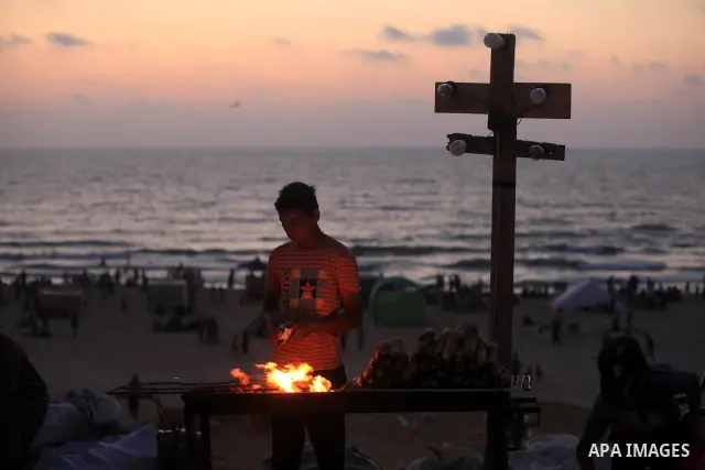 A Palestinian vendor sells grilled corn at Gaza beach on 13 July 2012 in Gaza City. Photo by Majdi Fathi