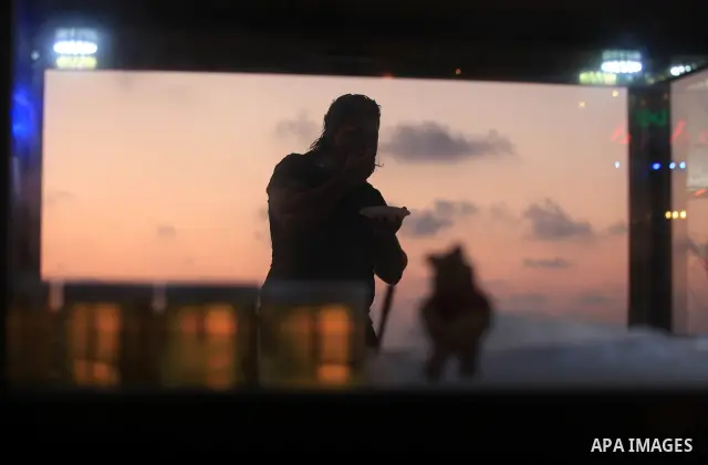 A Palestinian man eats sweets at Gaza beach on 13 July 2012 in Gaza City. Photo by Majdi Fathi