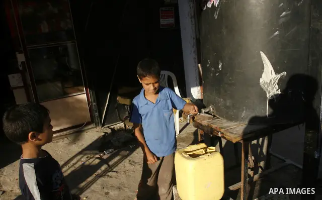 A Palestinian child fills bottles a potable water in the Rafah refugee camp in the southern Gaza Strip on July 14, 2012. Photo by Eyad Al Baba