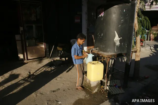 A Palestinian child fills bottles a potable water in the Rafah refugee camp in the southern Gaza Strip on July 14, 2012. Photo by Eyad Al Baba