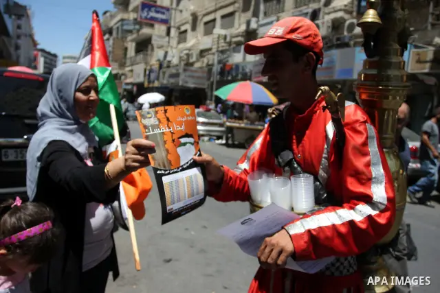 Palestinian protestors hold posters and graphics during a protest demanding Palestinian merchants to boycott Israeli settlement products and goods, and support national economy in the West Bank city of Ramallah ,on July...