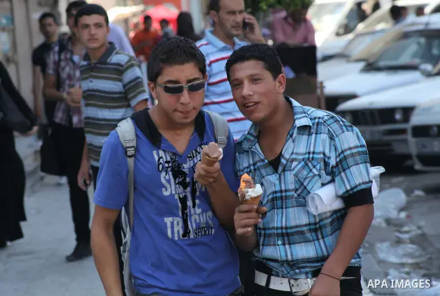 Palestinians eat ice-cream in the street during hot weather in Gaza city, July 16, 2012. The temperature of the Gaza strip reaches more than 33 degrees Celsius and 61% humidity, Gazans escape to the beach and out from th...