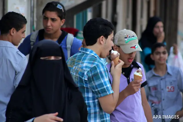 Palestinians eat ice-cream in the street during hot weather in Gaza city, July 16, 2012. The temperature of the Gaza strip reaches more than 33 degrees Celsius and 61% humidity, Gazans escape to the beach and out from th...