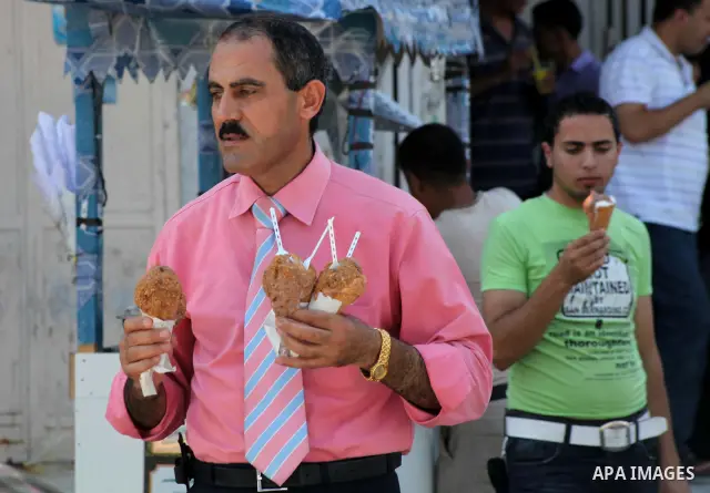 Palestinians eat ice-cream in the street during hot weather in Gaza city, July 16, 2012. The temperature of the Gaza strip reaches more than 33 degrees Celsius and 61% humidity, Gazans escape to the beach and out from th...