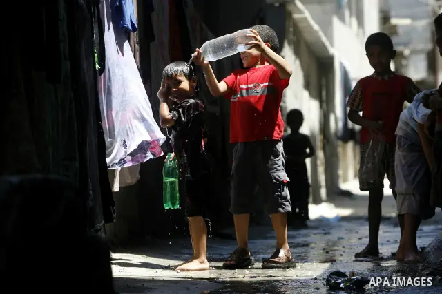 Palestinian children bathe outside their home in the Rafah refugee camp in the southern Gaza Strip on July 17, 2012. The temperature of the Gaza strip reaches more than 35 degrees Celsius and 50% humidity, Gazans escape...