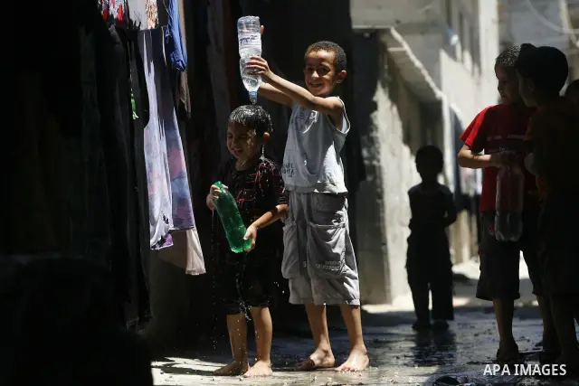 Palestinian children bathe outside their home in the Rafah refugee camp in the southern Gaza Strip on July 17, 2012. The temperature of the Gaza strip reaches more than 35 degrees Celsius and 50% humidity, Gazans escape...