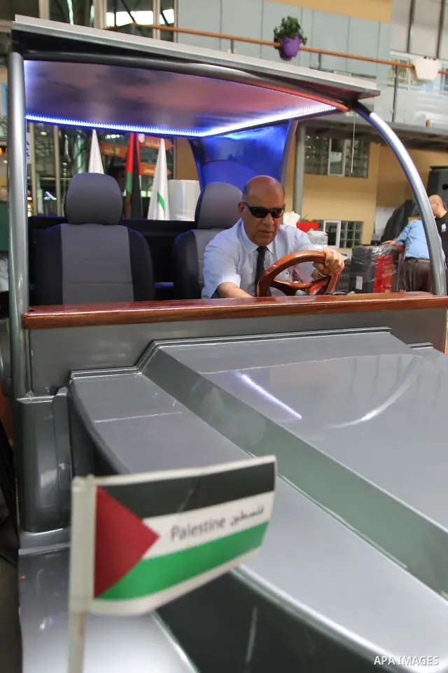 Palestinian staff member introduces the first Palestinian electric car to visitors during an international environment expo held in the West Bank city of Hebron, on 17 July 2012. The exhibitors attended the expo bringing...