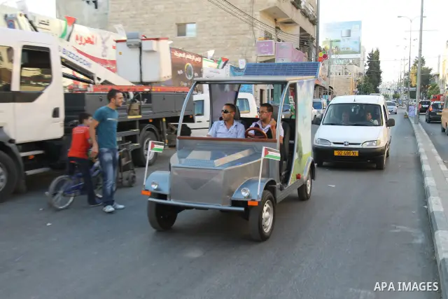 Palestinians inspect the first Palestinian electric car during an international environment expo held in the West Bank city of Hebron, on 17 July 2012. The exhibitors attended the expo bringing such new technologies and...