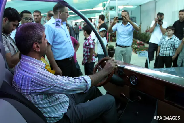 Palestinians inspect the first Palestinian electric car during an international environment expo held in the West Bank city of Hebron, on 17 July 2012. The exhibitors attended the expo bringing such new technologies and...