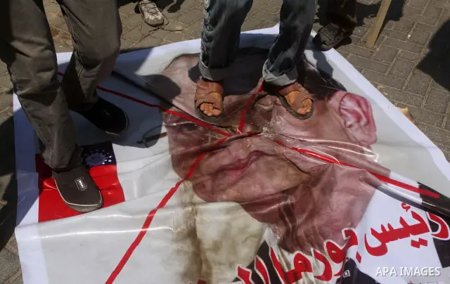 Palestinian supporters of the Popular Resistance Movement linked Hamas, burn a U.S. flag and hold a poster of Myanmar's President Thein Sein reading in Arabic "President of Burma despicable," during a demonstration calli...