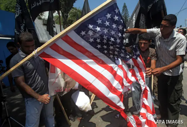 Palestinian supporters of the Popular Resistance Movement linked Hamas, burn a U.S. flag and hold a poster of Myanmar's President Thein Sein reading in Arabic "President of Burma despicable," during a demonstration calli...