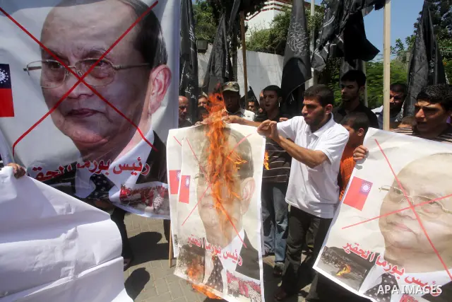 Palestinian supporters of the Popular Resistance Movement linked Hamas, burn a U.S. flag and hold a poster of Myanmar's President Thein Sein reading in Arabic "President of Burma despicable," during a demonstration calli...