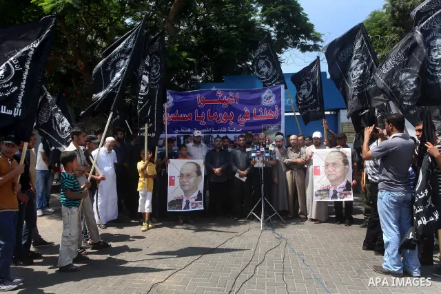 A Palestinian supporter of the Popular Resistance Movement linked Hamas, holds a sword as others carry posters of Myanmar's President Thein Sein during a demonstration calling to stop killing the Burmese Muslims in Myanm...