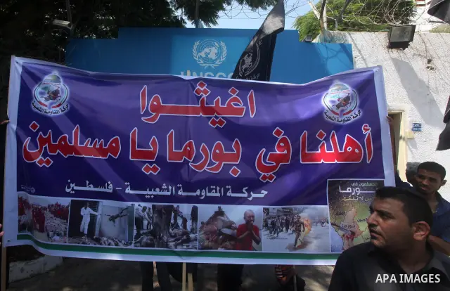 A Palestinian supporter of the Popular Resistance Movement linked Hamas, holds a sword as others carry posters of Myanmar's President Thein Sein during a demonstration calling to stop killing the Burmese Muslims in Myanm...