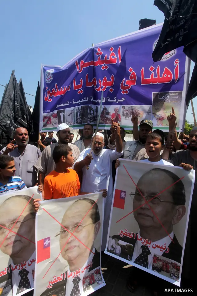 A Palestinian supporter of the Popular Resistance Movement linked Hamas, holds a sword as others carry posters of Myanmar's President Thein Sein during a demonstration calling to stop killing the Burmese Muslims in Myanm...