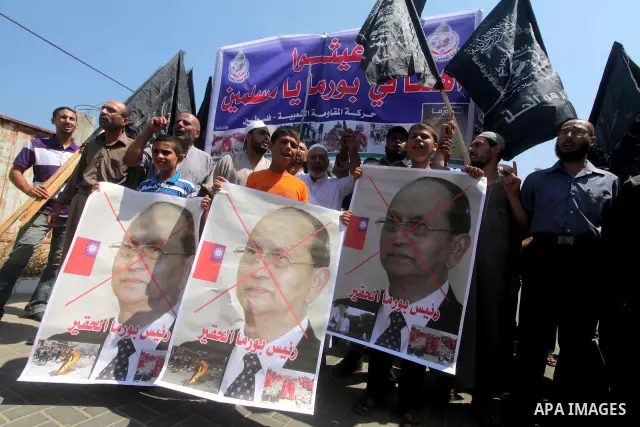 A Palestinian supporter of the Popular Resistance Movement linked Hamas, holds a sword as others carry posters of Myanmar's President Thein Sein during a demonstration calling to stop killing the Burmese Muslims in Myanm...