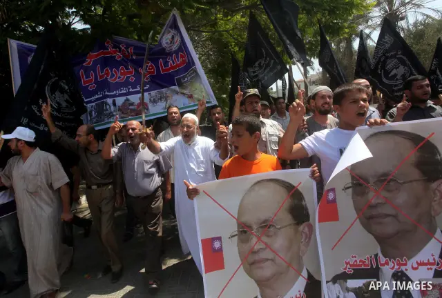 A Palestinian supporter of the Popular Resistance Movement linked Hamas, holds a sword as others carry posters of Myanmar's President Thein Sein during a demonstration calling to stop killing the Burmese Muslims in Myanm...