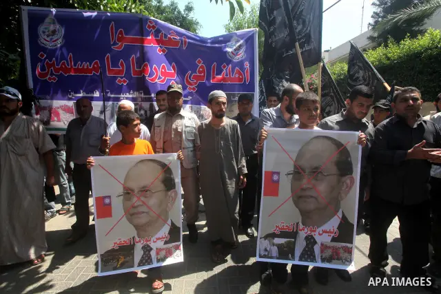A Palestinian supporter of the Popular Resistance Movement linked Hamas, holds a sword as others carry posters of Myanmar's President Thein Sein during a demonstration calling to stop killing the Burmese Muslims in Myanm...