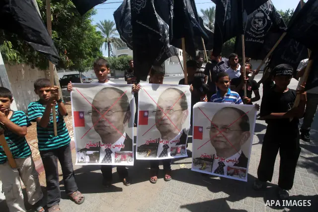 A Palestinian supporter of the Popular Resistance Movement linked Hamas, holds a sword as others carry posters of Myanmar's President Thein Sein during a demonstration calling to stop killing the Burmese Muslims in Myanm...