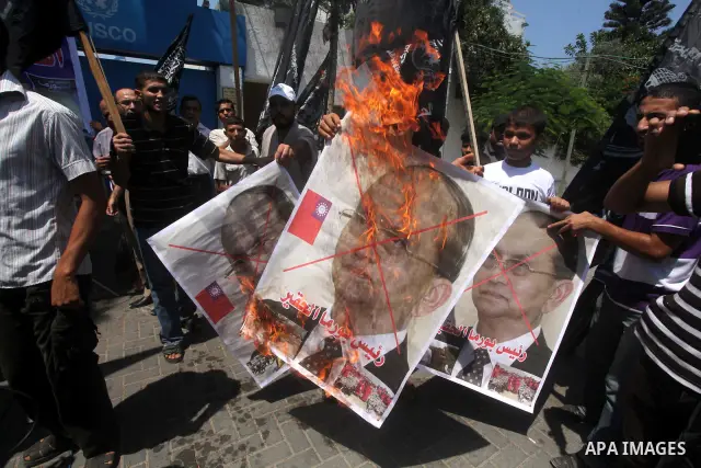 Palestinian supporters of the Popular Resistance Movement linked Hamas, burn a U.S. flag and hold a poster of Myanmar's President Thein Sein reading in Arabic "President of Burma despicable," during a demonstration calli...