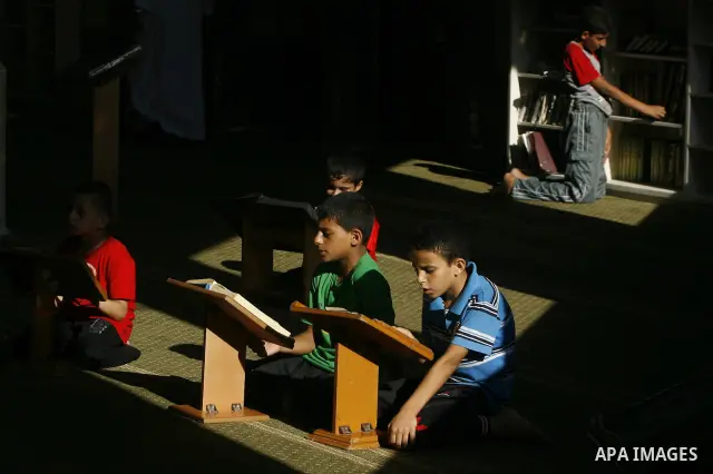 Palestinian boys read verses from the Quran during a class on how to save Islam's holy book, at a mosque in Rafah, southern Gaza city, on July 18, 2012. Photo by Eyad Al Baba