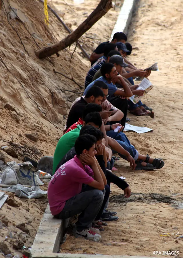 Palestinian secondary school students read a local newspaper to find their results in Gaza city on July 19, 2012. The Ministry of Education in Gaza Strip and the West Bank announced the results together. Photo by Ashraf...