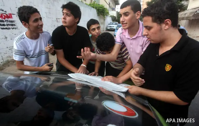 Palestinian secondary school students read a local newspaper to find their results in Gaza city on July 19, 2012. The Ministry of Education in Gaza Strip and the West Bank announced the results together. Photo by Ashraf...