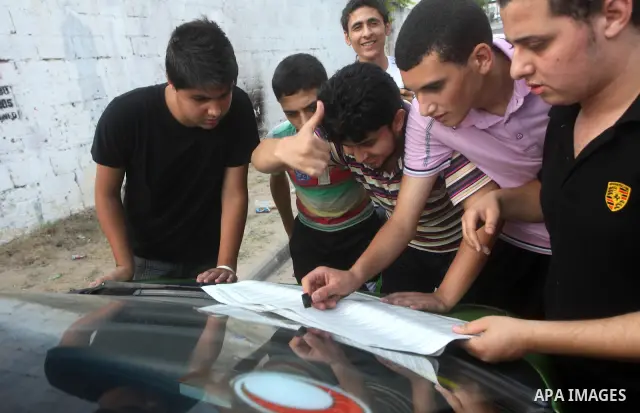 Palestinian secondary school students read a local newspaper to find their results in Gaza city on July 19, 2012. The Ministry of Education in Gaza Strip and the West Bank announced the results together. Photo by Ashraf...