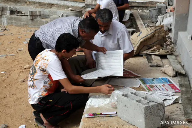 Palestinian secondary school students read a local newspaper to find their results in Gaza city on July 19, 2012. The Ministry of Education in Gaza Strip and the West Bank announced the results together. Photo by Ashraf...