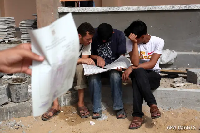 Palestinian secondary school students read a local newspaper to find their results in Gaza city on July 19, 2012. The Ministry of Education in Gaza Strip and the West Bank announced the results together. Photo by Ashraf...