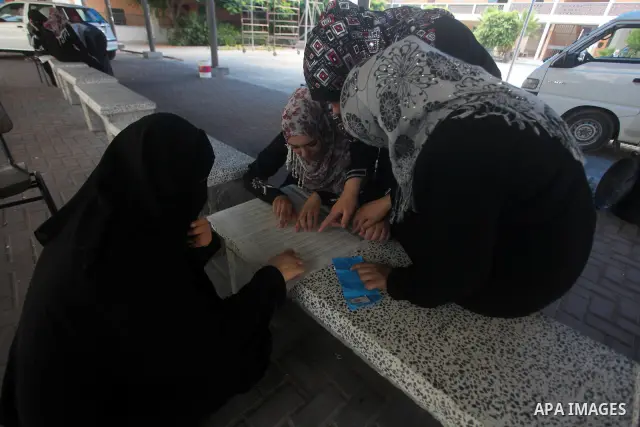 Palestinian secondary school students read a local newspaper to find their results in Gaza city on July 19, 2012. The Ministry of Education in Gaza Strip and the West Bank announced the results together. Photo by Ashraf...