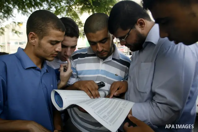 Palestinian secondary school students read a local newspaper to find their results in Rafah in the southern Gaza Strip on July 19, 2012. The Ministry of Education in Gaza Strip and the West Bank announced the results tog...