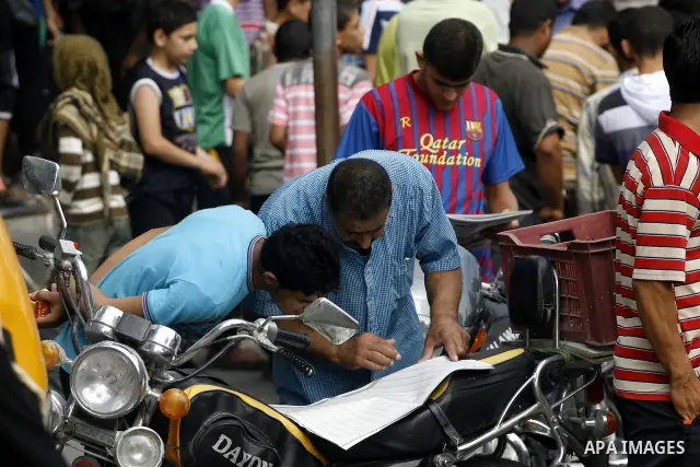 Palestinian relatives students read a local newspaper to find their results in Rafah in the southern Gaza Strip on July 19, 2012. The Ministry of Education in Gaza Strip and the West Bank announced the results together....