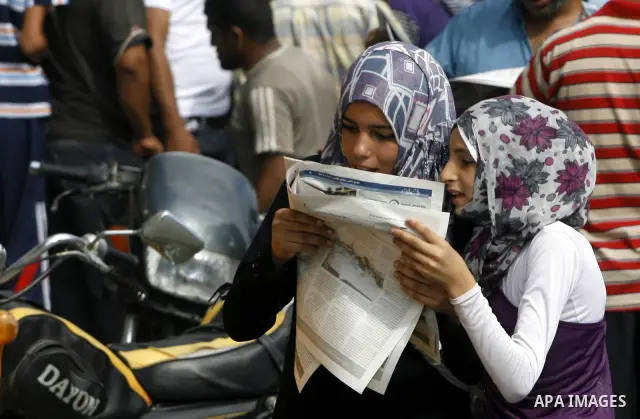 Palestinian secondary school students read a local newspaper to find their results in Rafah in the southern Gaza Strip on July 19, 2012. The Ministry of Education in Gaza Strip and the West Bank announced the results tog...