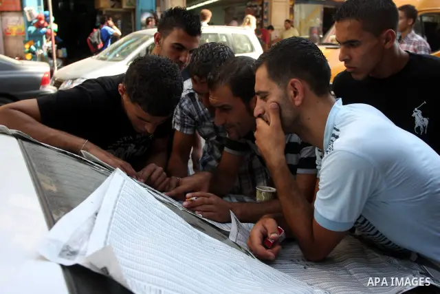 Palestinian high school students read a local newspaper to find their results in Gaza city on July 19, 2012. The Ministry of Education in Gaza Strip and the West Bank announced the results together. Photo by Issam Rimawi