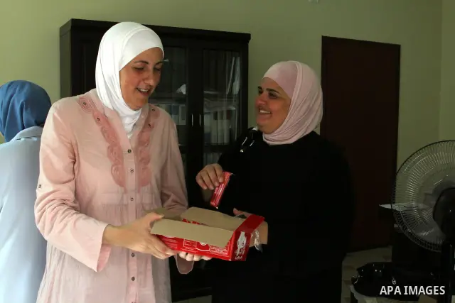 A Palestinian woman gives candy after heard the results of final exams of her high school daughter known as "Tawjihi" in the West Bank city of Nablus, on July 19, 2012. The Ministry of Education in Gaza Strip announced t...