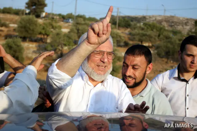 Hamas speaker of the Palestinian parliament Aziz Dweik waves to his supporters after he was released from Israeli prison, at the Beit Sira roadblock in the West Bank on 19 July 2012. The Israeli army arrested Dweik on Ja...