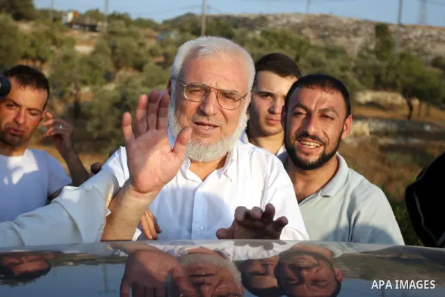 Hamas speaker of the Palestinian parliament Aziz Dweik waves to his supporters after he was released from Israeli prison, at the Beit Sira roadblock in the West Bank on 19 July 2012. The Israeli army arrested Dweik on Ja...