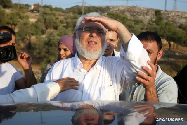 Hamas speaker of the Palestinian parliament Aziz Dweik waves to his supporters after he was released from Israeli prison, at the Beit Sira roadblock in the West Bank on 19 July 2012. The Israeli army arrested Dweik on Ja...