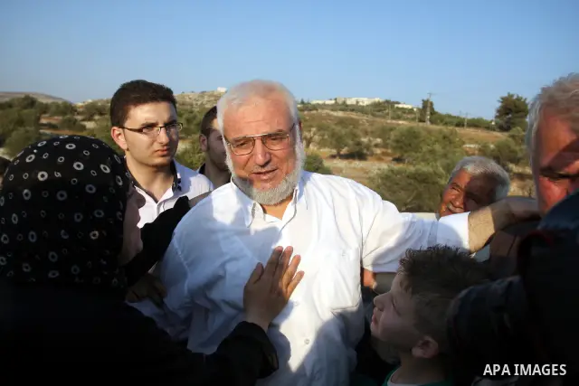 Hamas speaker of the Palestinian parliament Aziz Dweik speaks to his family after he was released from Israeli prison, at the Beit Sira roadblock in the West Bank on 19 July 2012. The Israeli army arrested Dweik on Janua...