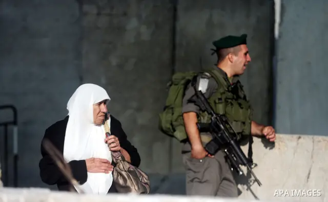 An Israeli border police officer checks documents of Palestinian women who wait to cross the Qalandia checkpoint on the outskirts of the West Bank city of Ramallah on July 20, 2012 as they head to the Al-Aqsa mosque comp...