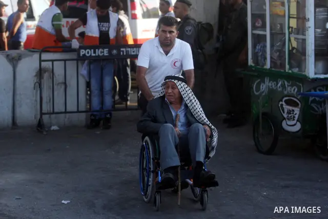 An Israeli border police officer checks documents of Palestinian man who wait to cross the Qalandia checkpoint on the outskirts of the West Bank city of Ramallah on July 20, 2012 as they head to the Al-Aqsa mosque compou...