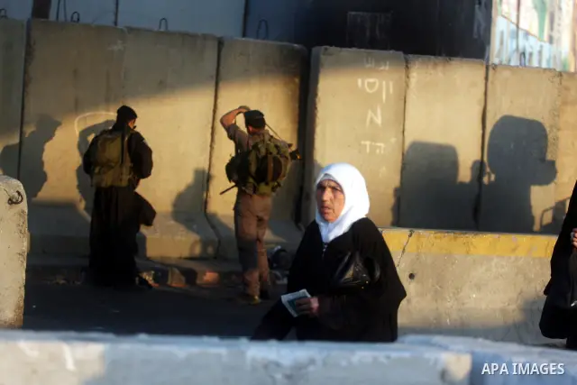 An Israeli border police officer checks documents of Palestinian women who wait to cross the Qalandia checkpoint on the outskirts of the West Bank city of Ramallah on July 20, 2012 as they head to the Al-Aqsa mosque comp...