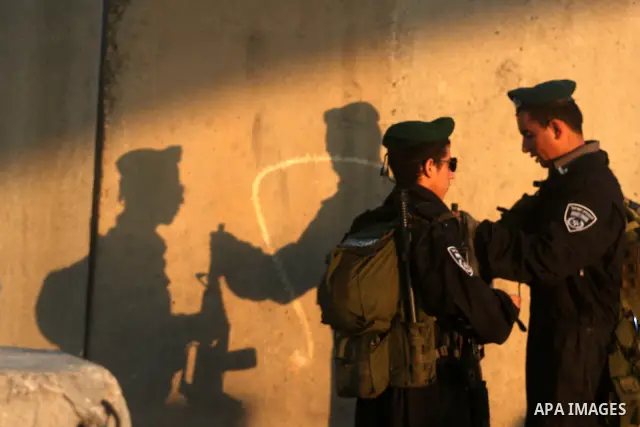 An Israeli border police officer checks documents of Palestinians who wait to cross the Qalandia checkpoint on the outskirts of the West Bank city of Ramallah on July 20, 2012 as they head to the Al-Aqsa mosque compound...