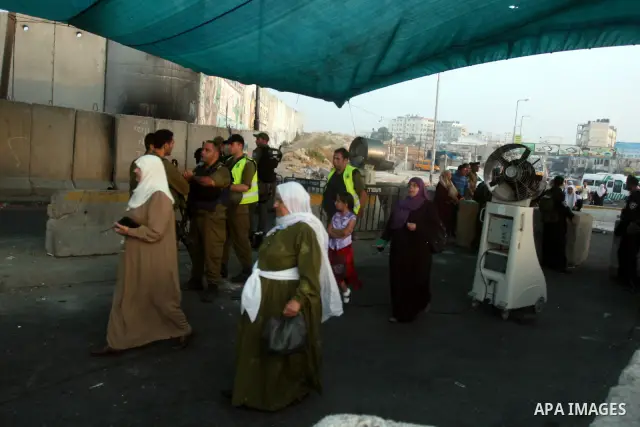 An Israeli border police officer checks documents of Palestinian women who wait to cross the Qalandia checkpoint on the outskirts of the West Bank city of Ramallah on July 20, 2012 as they head to the Al-Aqsa mosque comp...