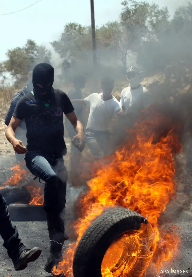 A Palestinian protester fires tires during clashes with Israeli troops as Palestinians protest against the Jewish settlement of Kdumim, near Nablus, West Bank, 20 July 2012. According to medical sources 16 Palestinians w...