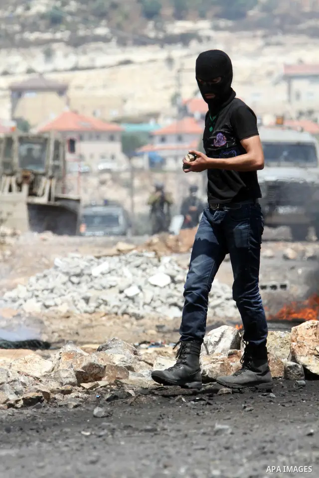 A Palestinian protestor throws stones at Israeli troops during clashes as they protest against the Jewish settlement of Kdumim, near Nablus, West Bank, 20 July 2012. According to medical sources 16 Palestinians were inju...