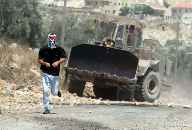 A Palestinian protestor throws stones at Israeli truck during clashes as they protest against the Jewish settlement of Kdumim, near Nablus, West Bank, 20 July 2012. According to medical sources 16 Palestinians were injur...