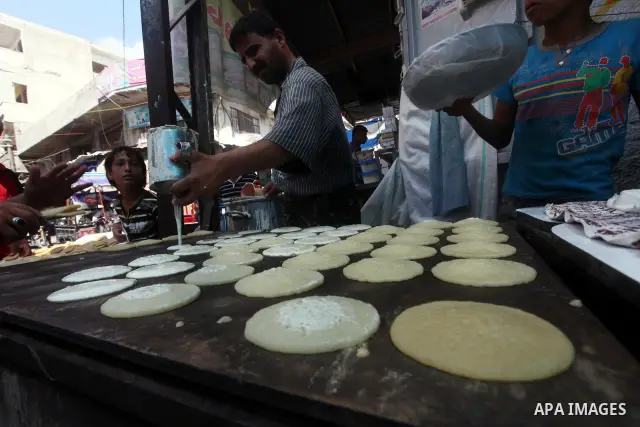 A Palestinian vendor prepares a traditional pancake known as "Qatayef" on the second day of the holy month of Ramadan, at a shop in Gaza City, on 21 July 2012. Muslims around the world abstain from eating, drinking and c...